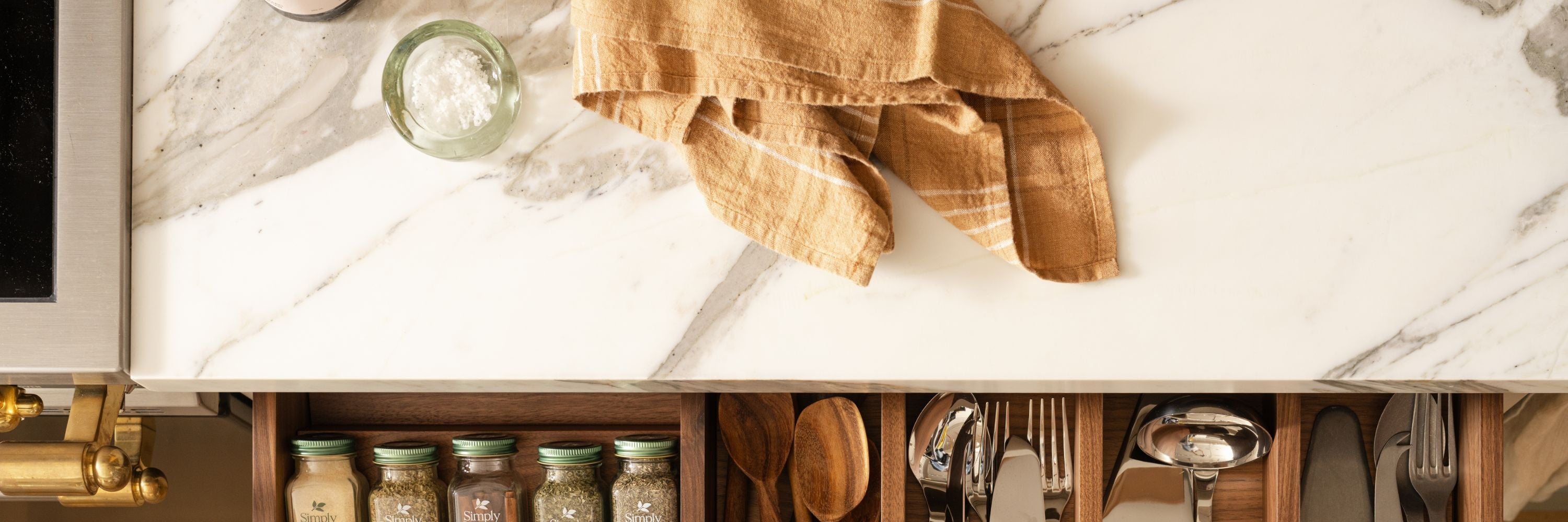 Ceramic bowls, glassware, terracotta serveware, and pantry staples styled on open kitchen shelves and marble countertop