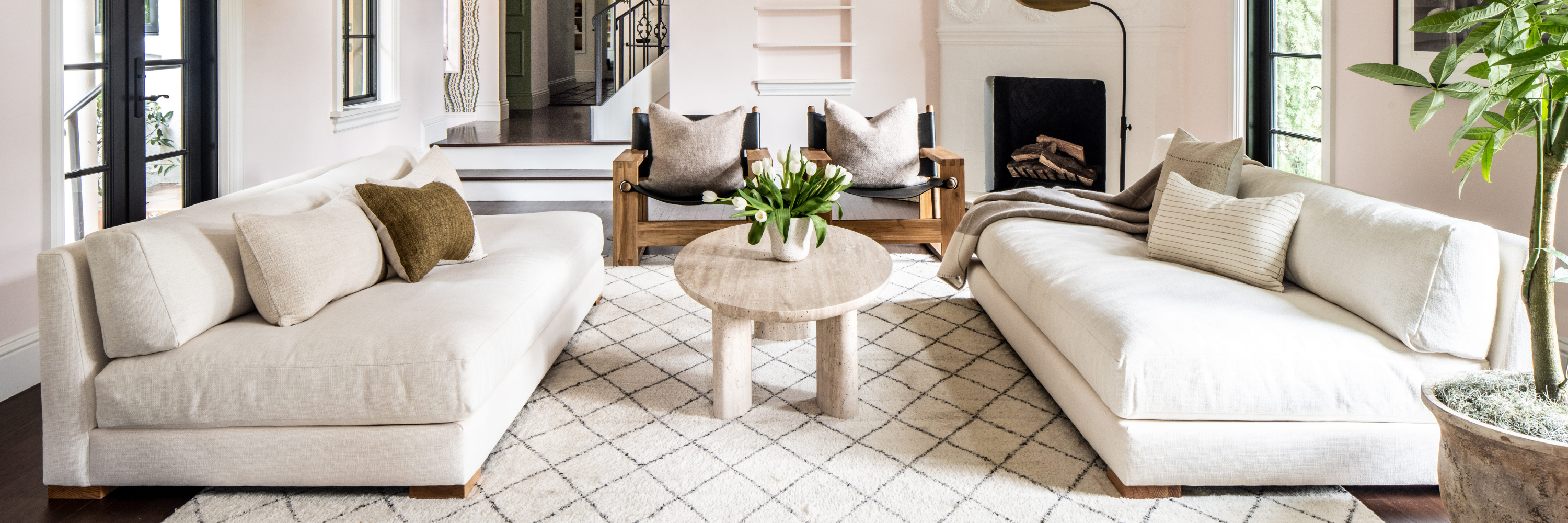 Soft-toned diamond-pattern rug grounding a living room with upholstered sofas and wood chairs