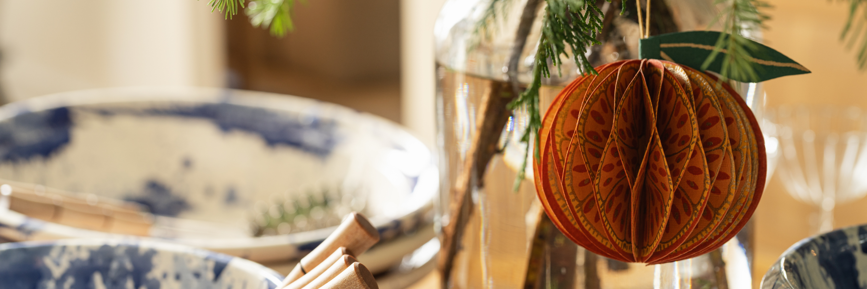 Natural evergreen arrangement with paper ornaments styled for holiday decorating and gifting