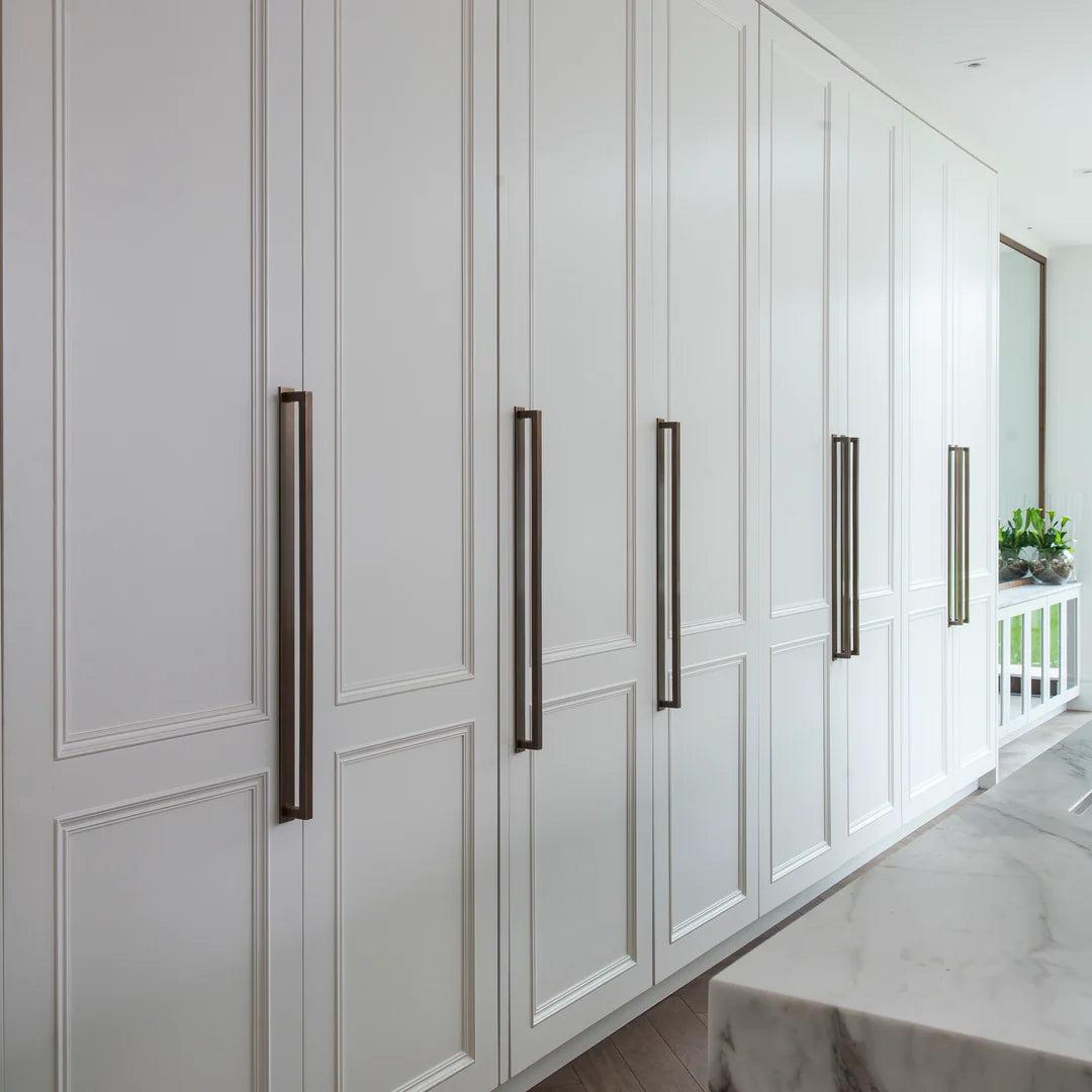 White kitchen cabinets with black handles in a modern kitchen setting.
