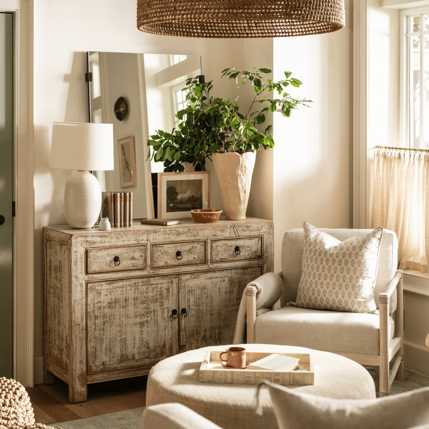 Whitewashed vintage sideboard styled with a lamp and greenery in a neutral living room by Calimia Home