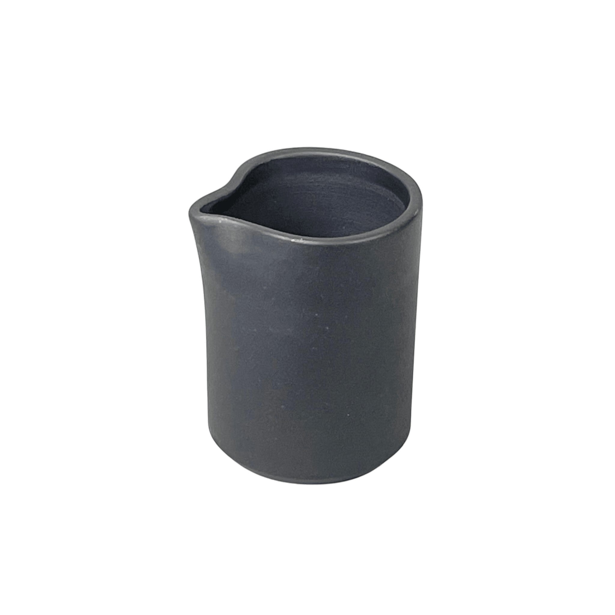 Bitters Co Barro pitcher in matte black clay with a minimalist cylindrical design and a small pouring spout.