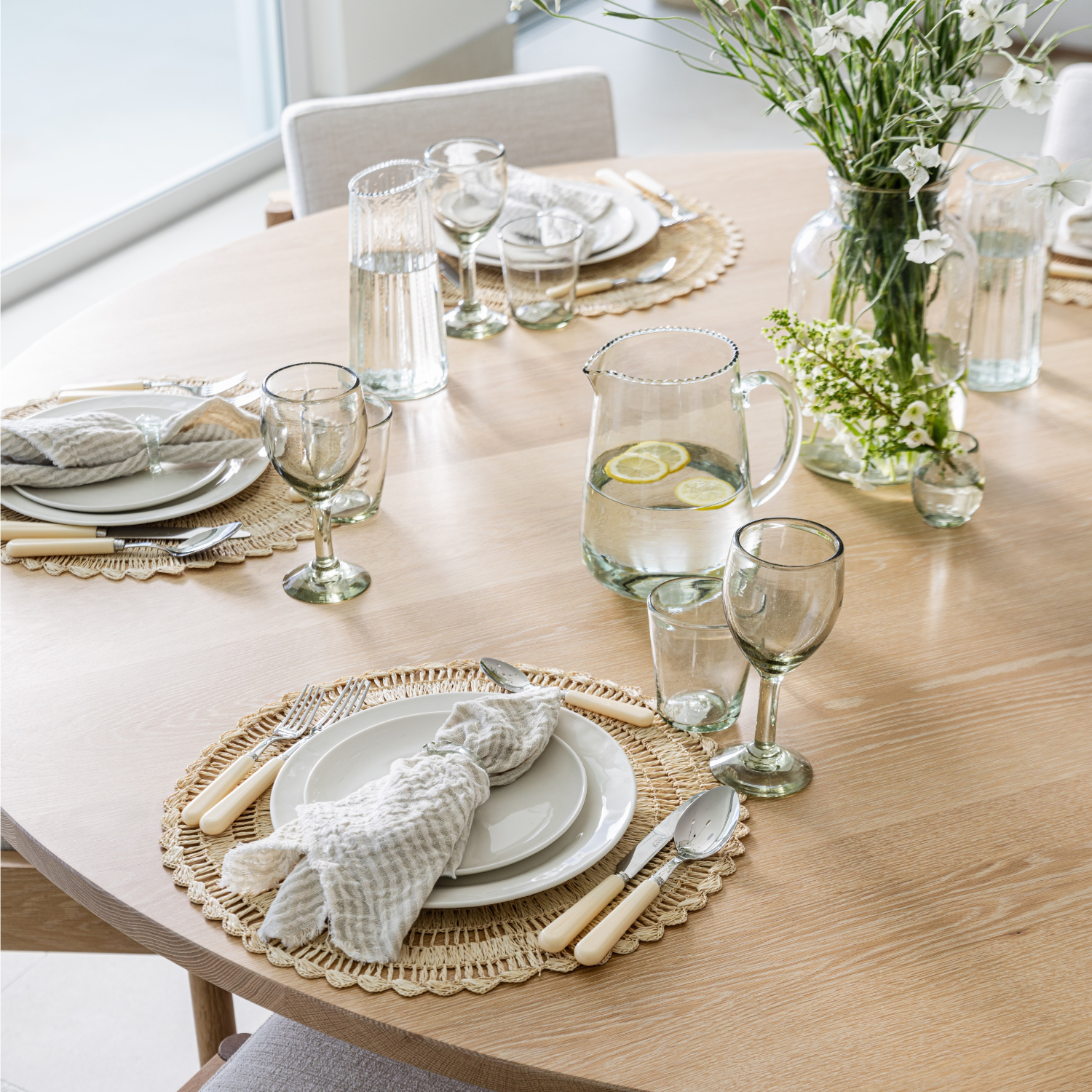 Dining table set with plates, glasses, and cutlery on a wooden surface.
