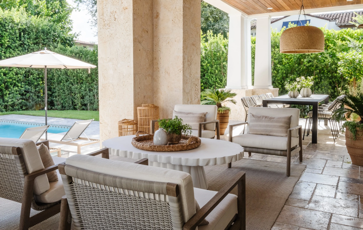 Covered patio lounge with woven seating and stone pavers in the Coral Way Craftsman home, Miami