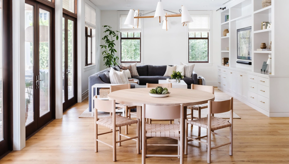 Open dining area with round white oak table, woven chairs, and bright white built-ins