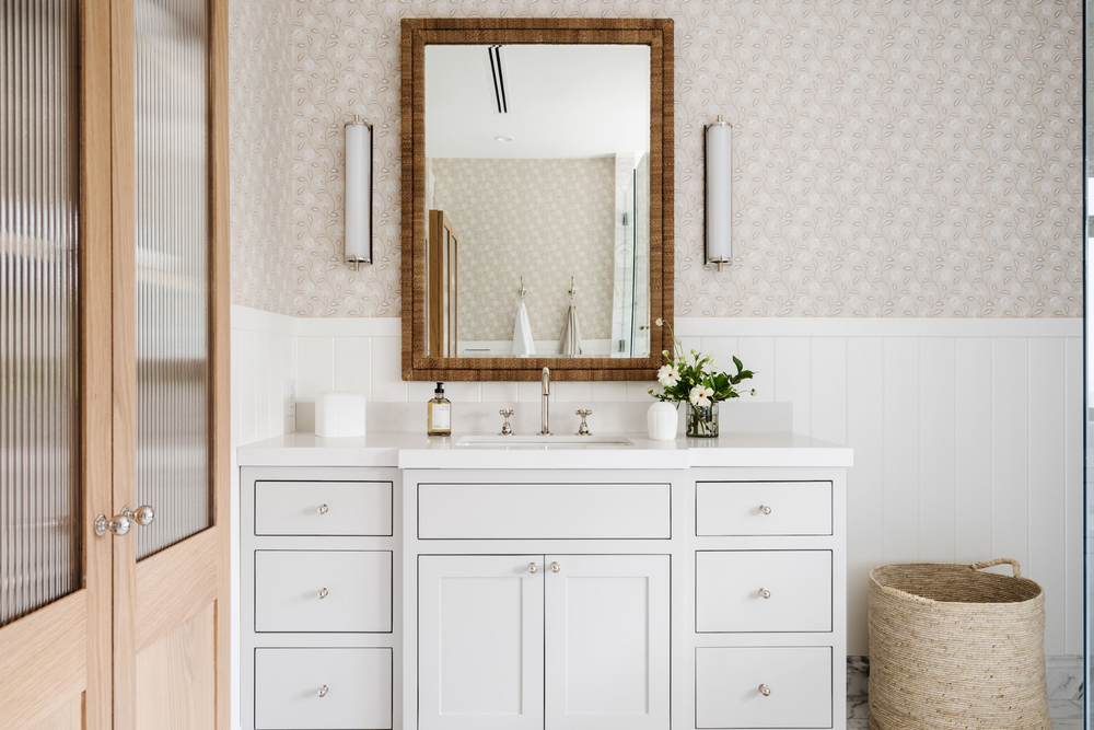 Soft gray vanity with antique wood mirror and patterned wallpaper, designed by Calimia Home