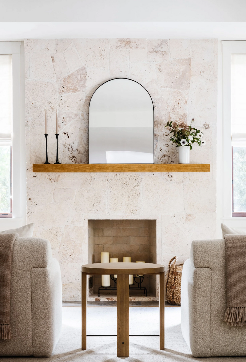 Limestone fireplace with floating wood mantel and arched mirror in the Coral Way Craftsman living room