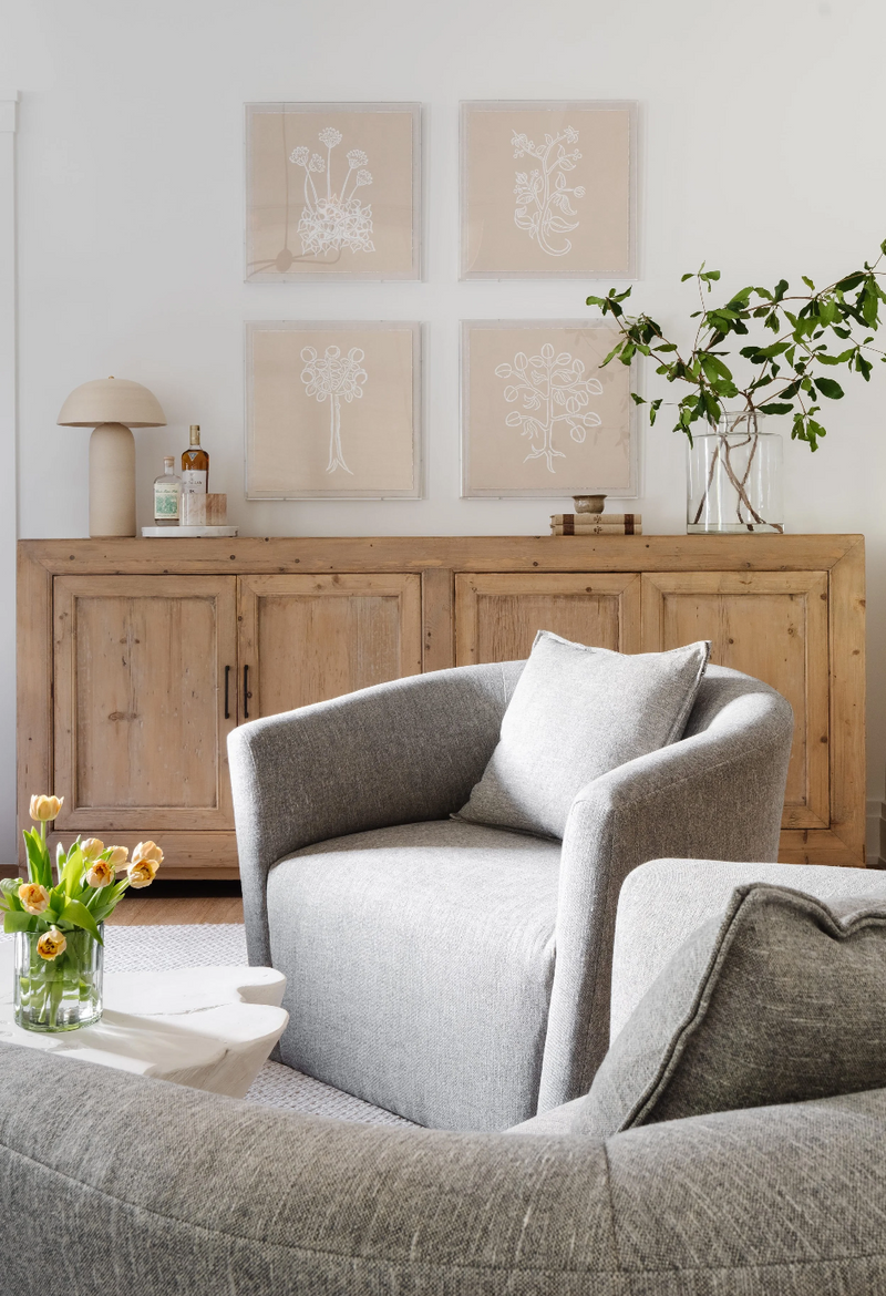 Reading corner with antique pine sideboard, botanical art grid, and gray swivel chair