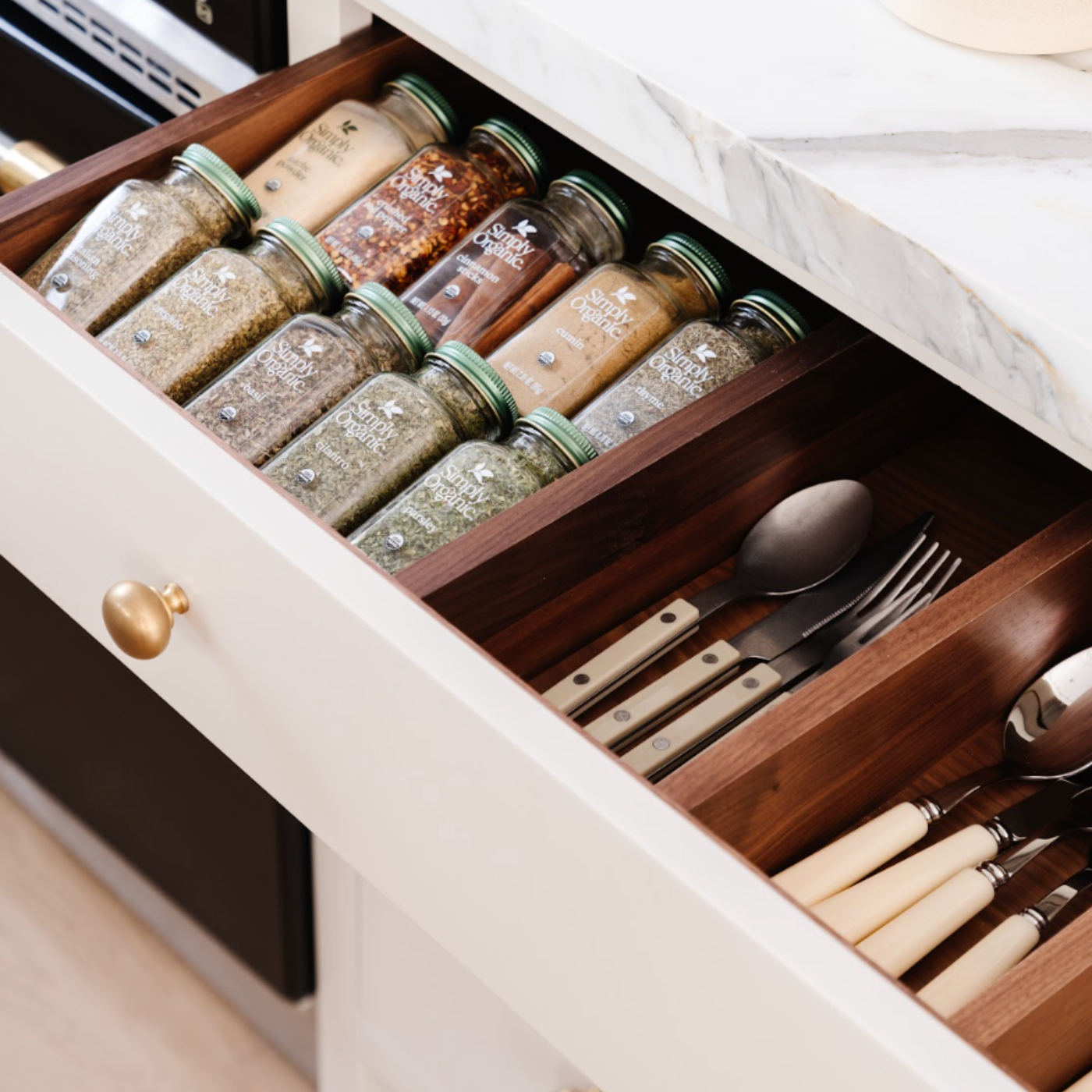 Custom kitchen drawer with spice jars and flatware organizers by Stoffer Home Cabinetry