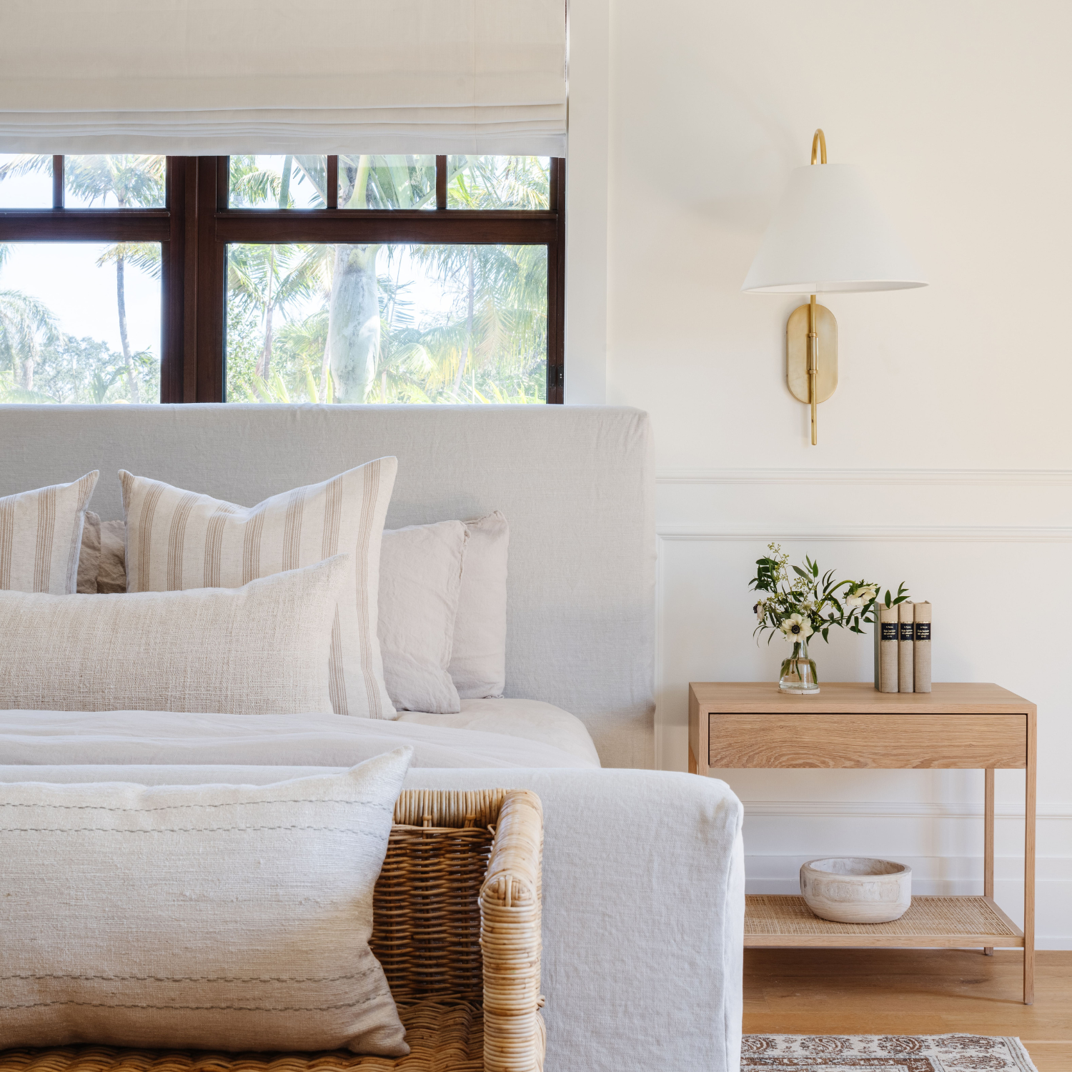 Serene white bedroom with layered linen bedding and oak nightstand designed by Calimia Home