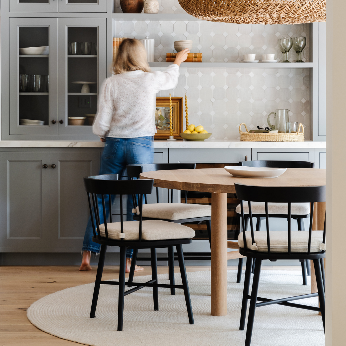 Designer styling open shelves in a gray kitchen with oak dining table and black spindle chairs