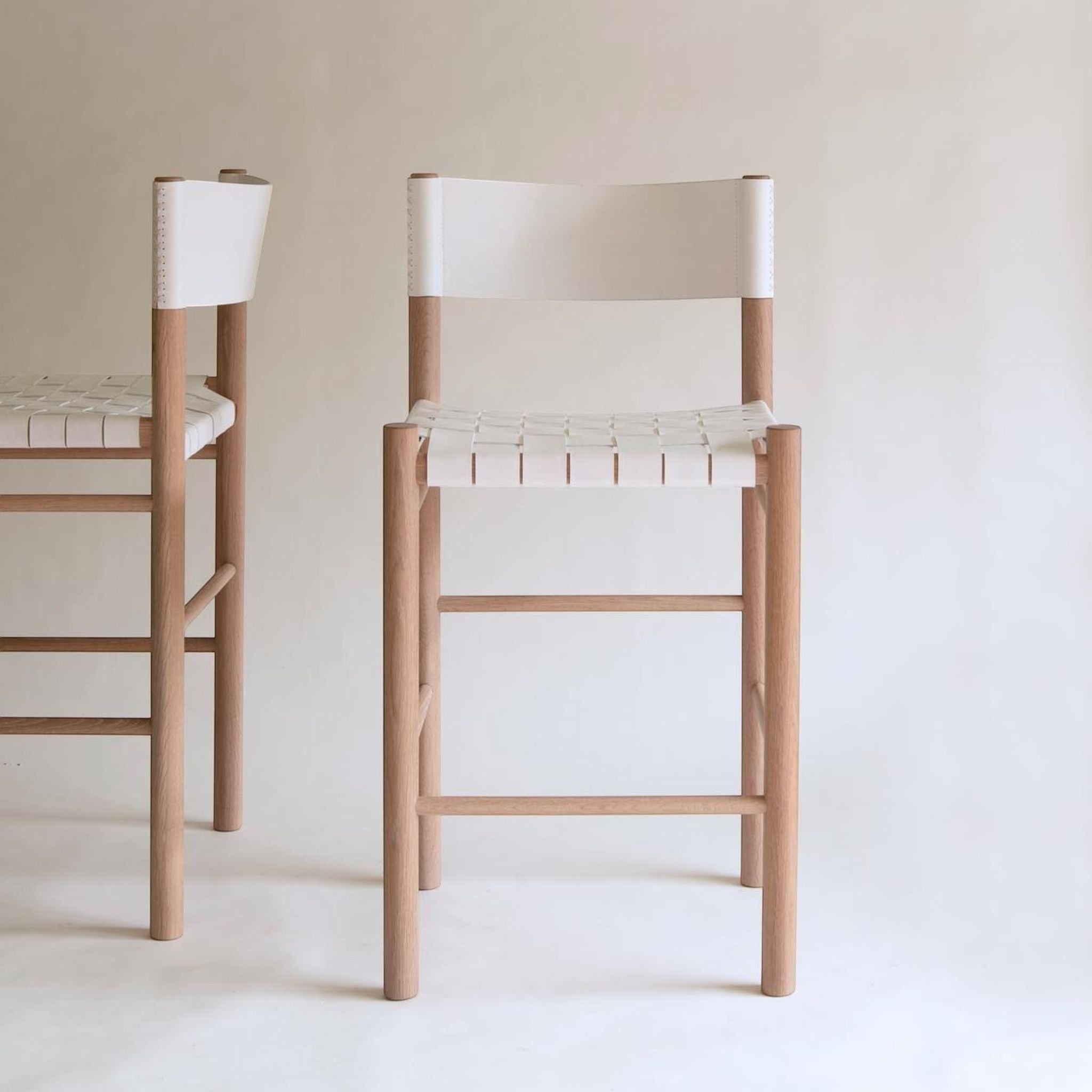 Calimia Home Flag counter stool with a solid oak frame and white woven leather seat in a minimalist design.
