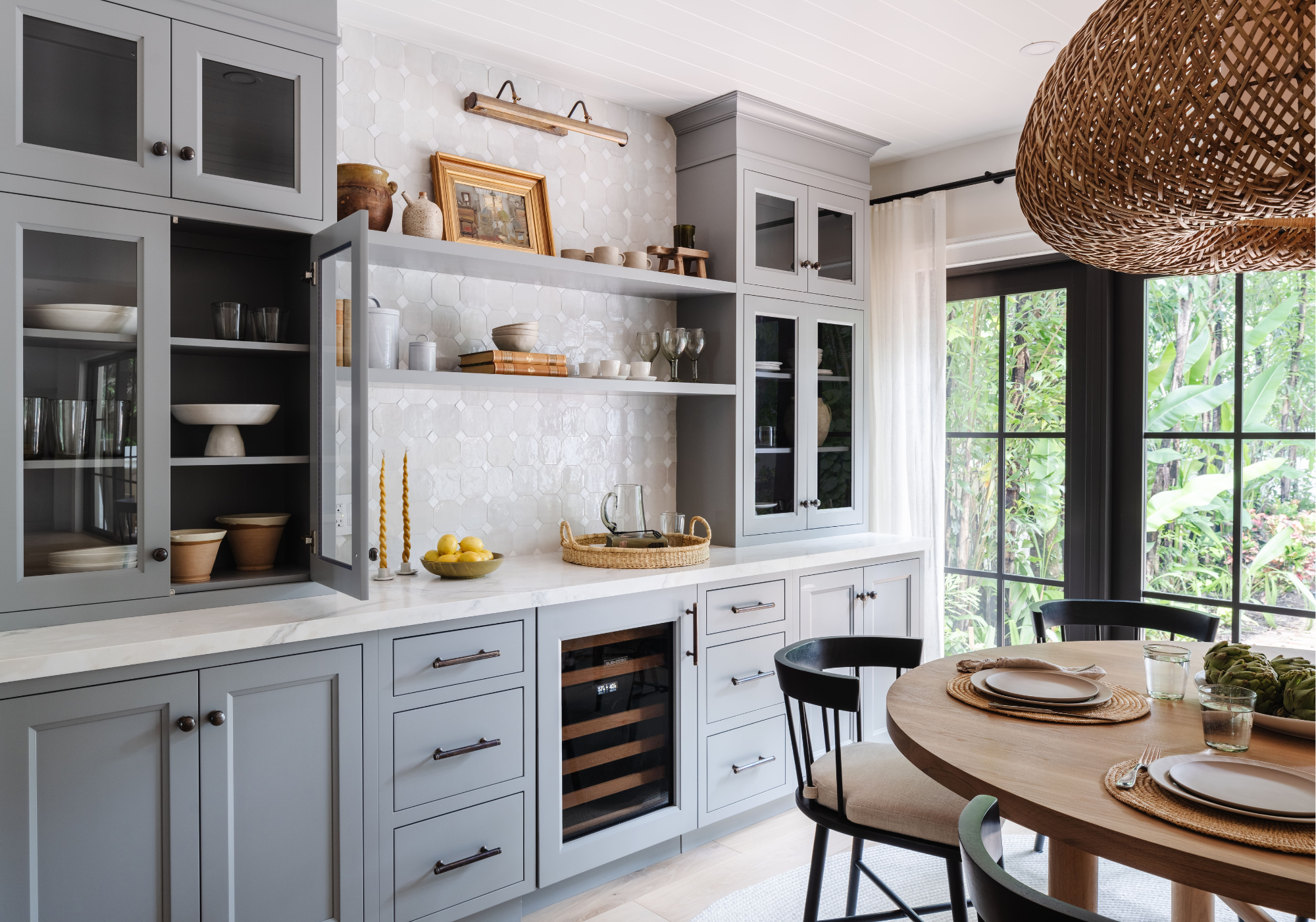 Light gray kitchen with open shelving and round dining table, full-service interior design by Calimia Home in Miami