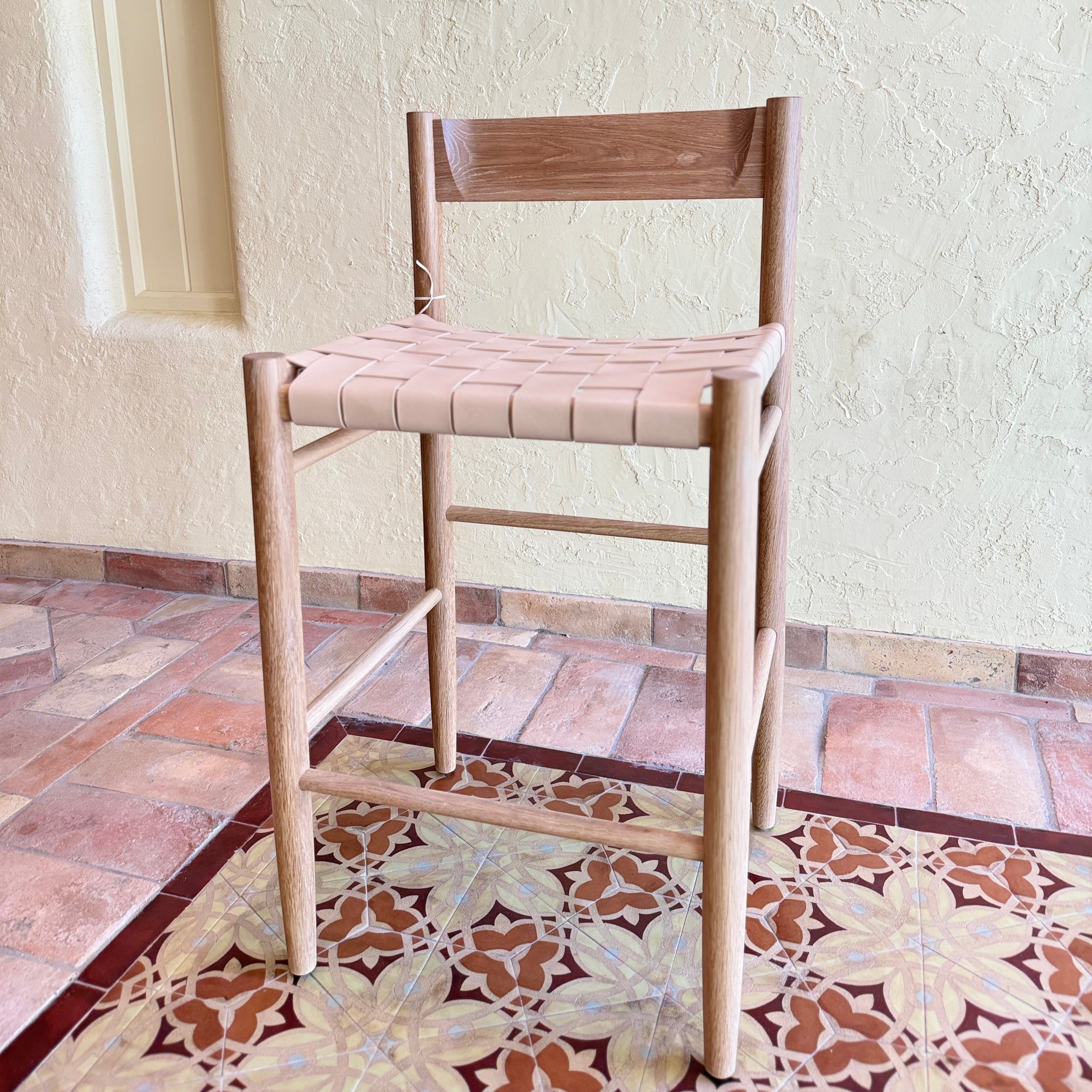 Calimia Home Gaon counter stool with a solid white oak frame and a woven natural leather seat and backrest.