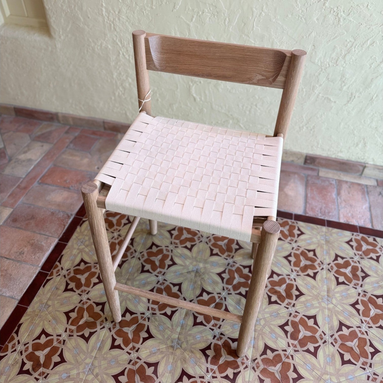 Calimia Home Gaon counter stool featuring a solid white oak frame and a woven light-toned seat with a backrest.