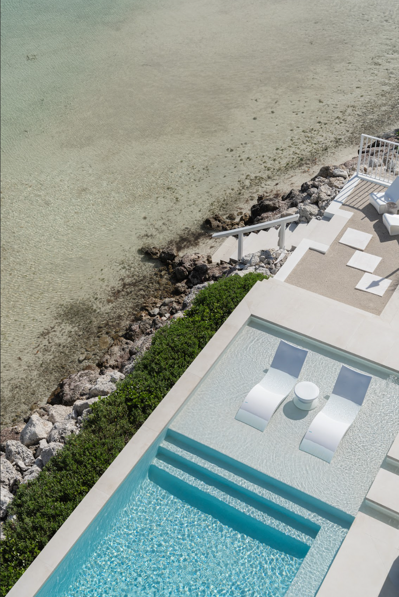Aerial view of the pool deck, loungers, and rocky shoreline at Peaceful Waters, Islamorada