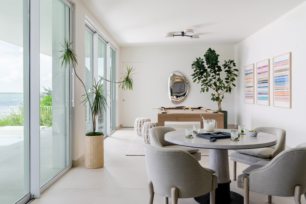 Light-filled dining area with oak table, coastal artwork, and sliding glass doors to the terrace