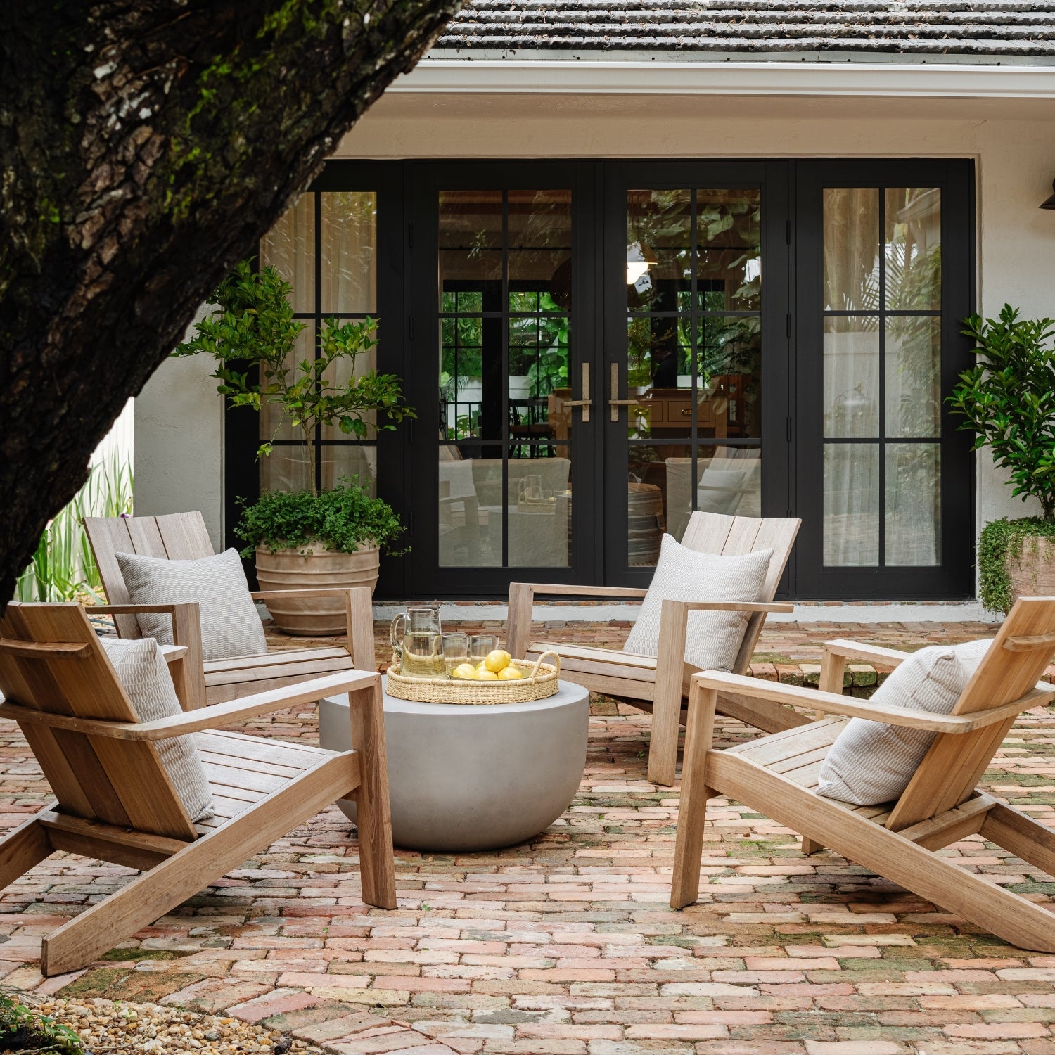 Brick patio with teak lounge chairs and black French doors — Raynolds Residence, a design project in Coconut Grove, Miami