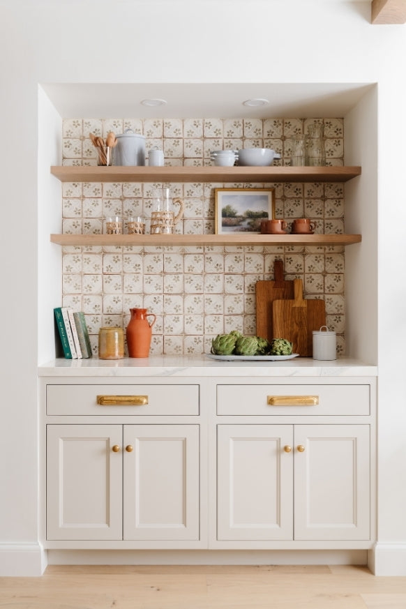 Butler's pantry with patterned tile, floating oak shelves, and brass hardware styled with artichokes