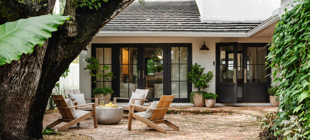 Renovated historic cottage with black steel doors and gravel courtyard seating in the Raynolds Residence, Coconut Grove