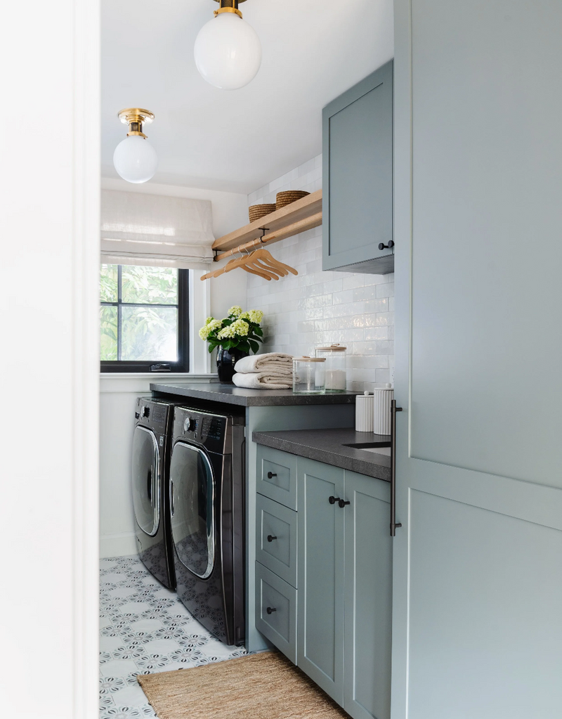 Blue-gray laundry room with patterned tile floor and brass globe lights in this Coconut Grove renovation