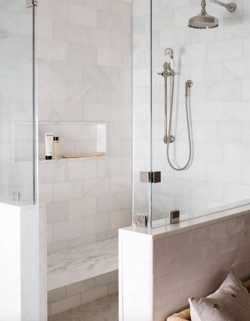 Marble walk-in shower with glass partition, rain shower head, and built-in niche