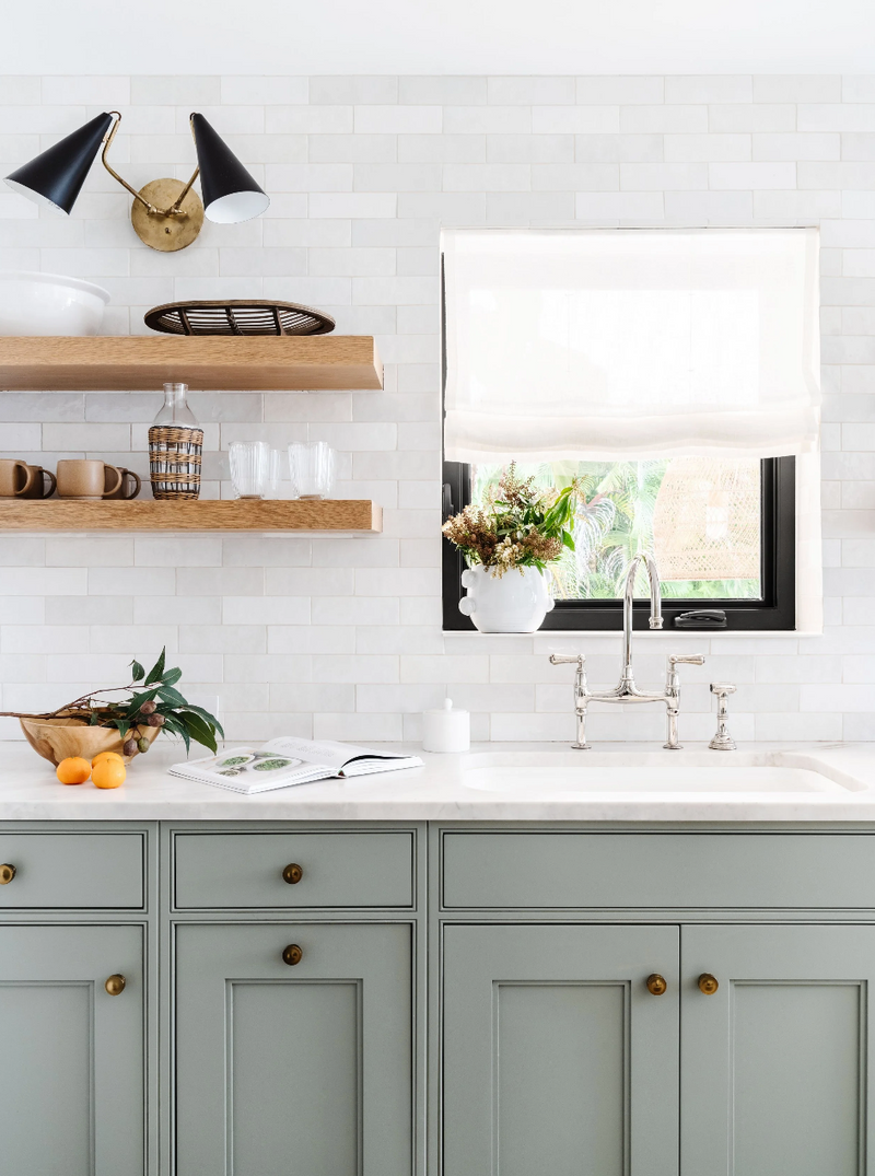 Sage cabinetry, open oak shelves, and handmade tile around the kitchen sink, Spanish in the Gables