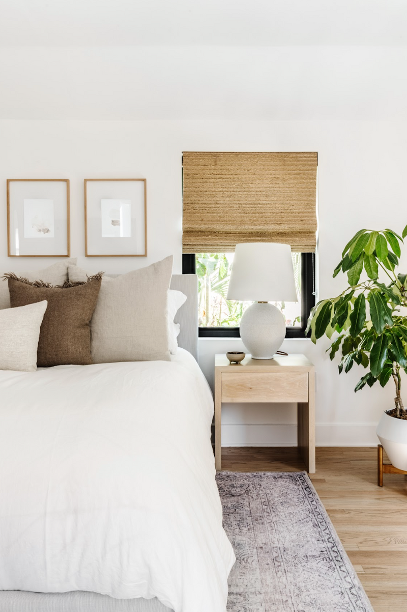 Neutral bedroom with white oak nightstand, ceramic lamp, and layered earth-tone pillows