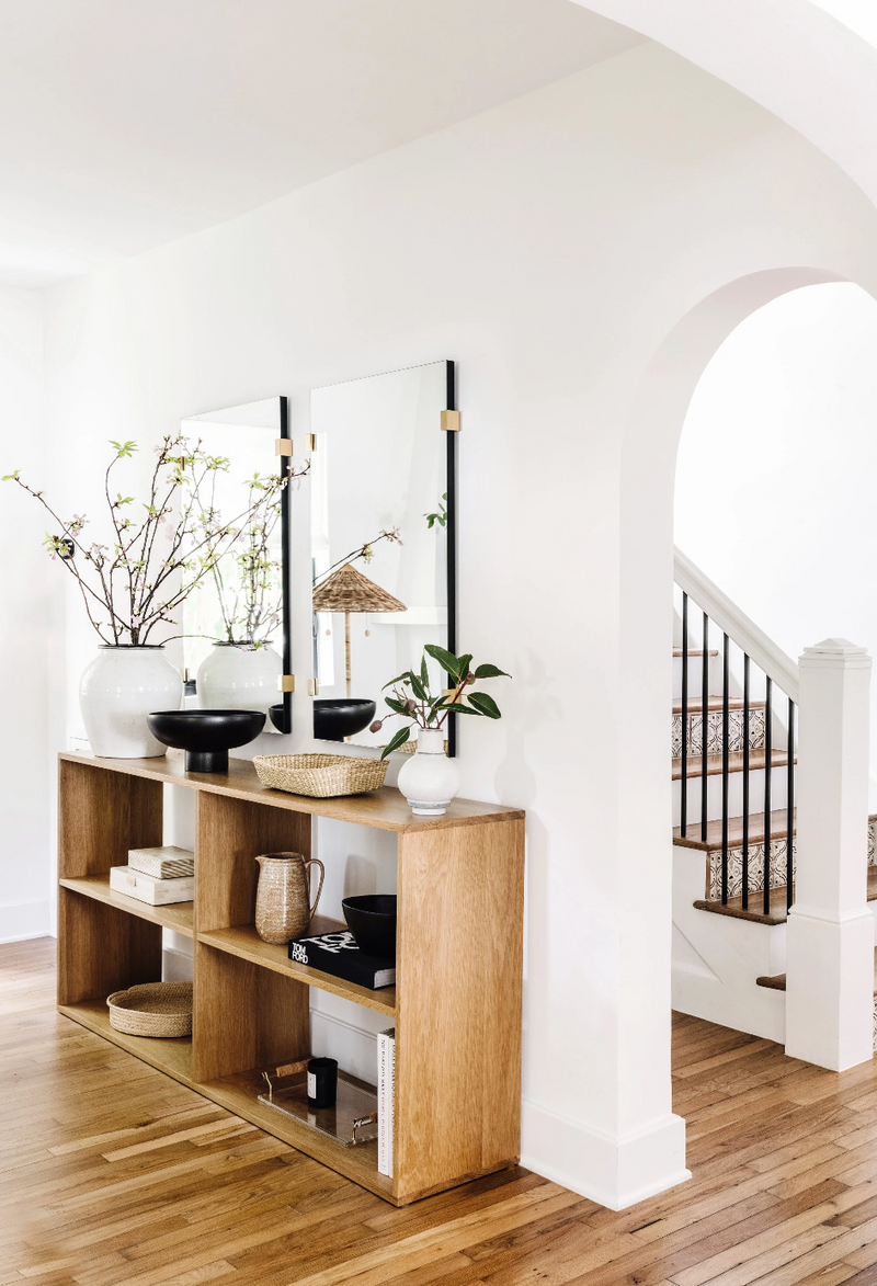 Oak console shelving with mirrors beside an arched stairway in the Coral Gables remodel