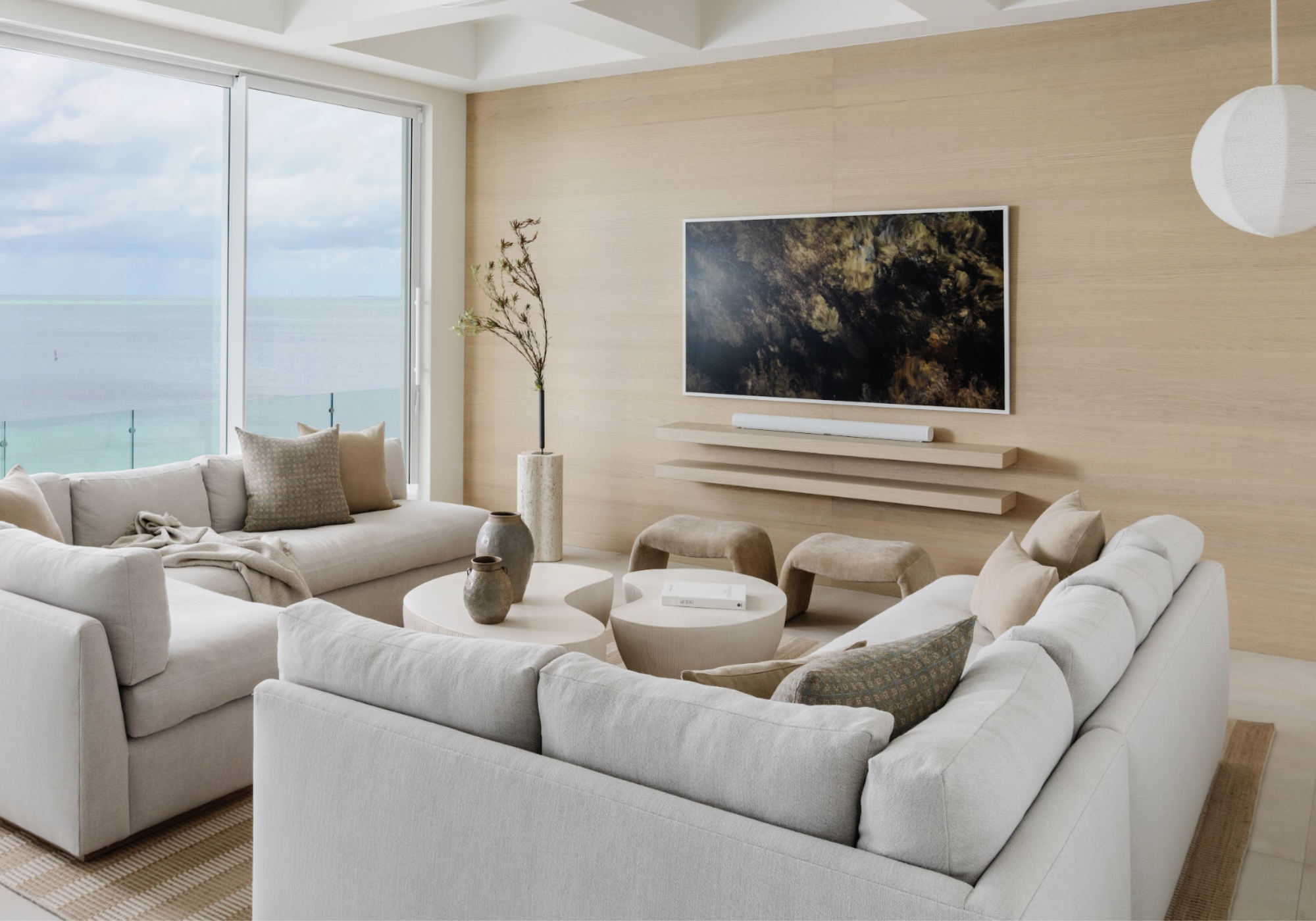 Room design by Calimia Home featuring a white sectional and wood-paneled wall in an oceanfront Miami living room