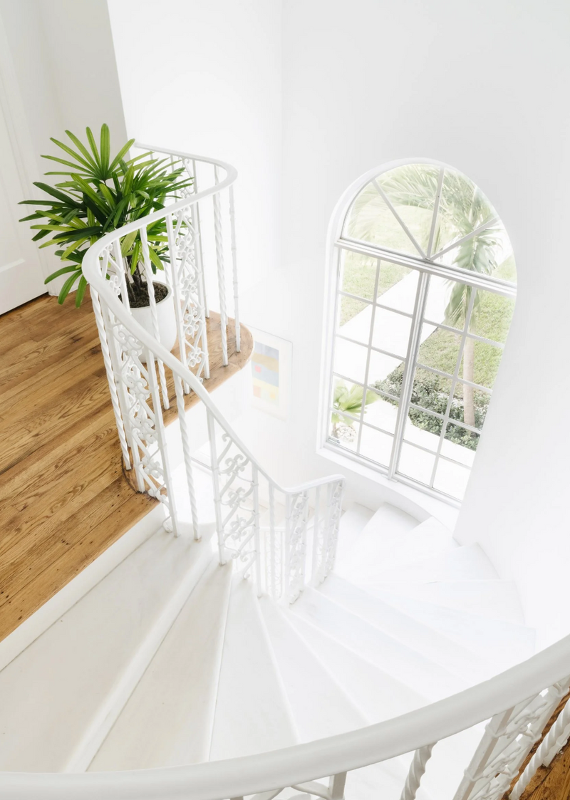 Curved white staircase with arched window and wood treads viewed from above