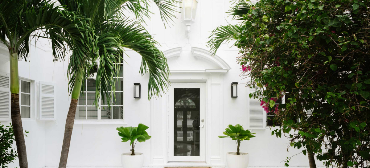 White Art Deco entry framed by palms at the Sunset Island residence in Miami Beach