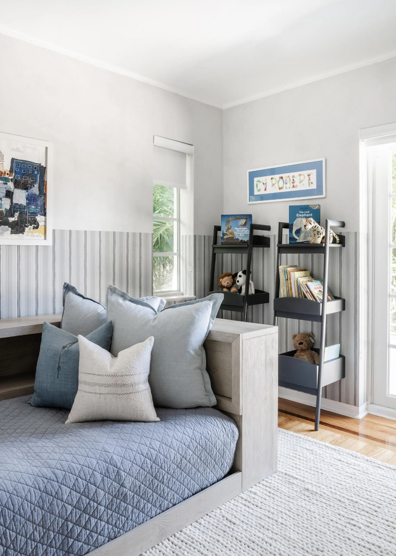 Blue-toned kids' bedroom with cozy daybed, layered pillows, and a ladder bookshelf