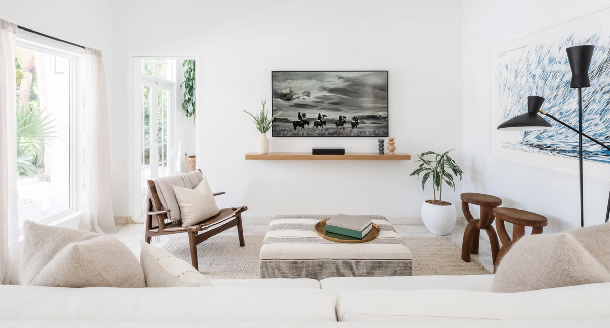 Airy living room with white sofas, walnut sling chairs, and surf photography in the Sunset Island residence