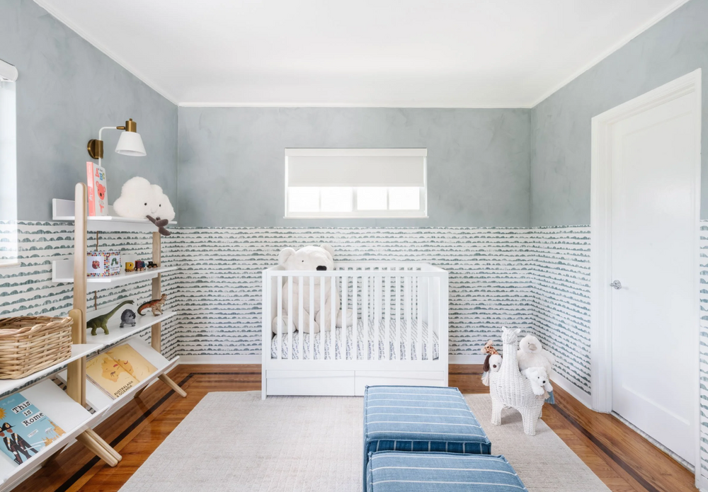 Nursery with white crib, soft blue wallpaper, and open shelving in the Sunset Island home