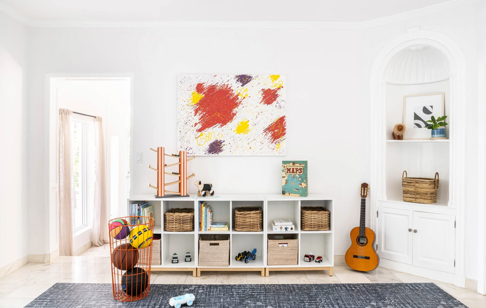 Playroom with low cubby storage, woven bins, a guitar, and colorful abstract art