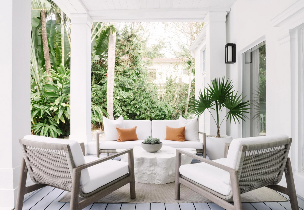 Covered porch lounge with gray teak armchairs and terracotta pillows, designed by Calimia Home