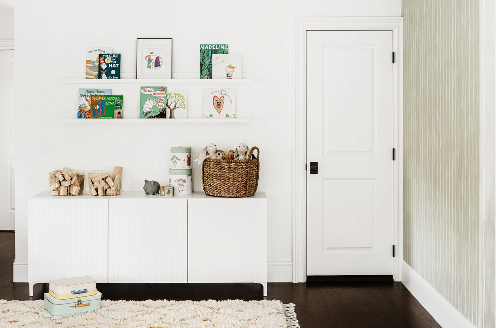 Children's room corner with picture-ledge bookshelves, fluted white cabinet, and woven basket