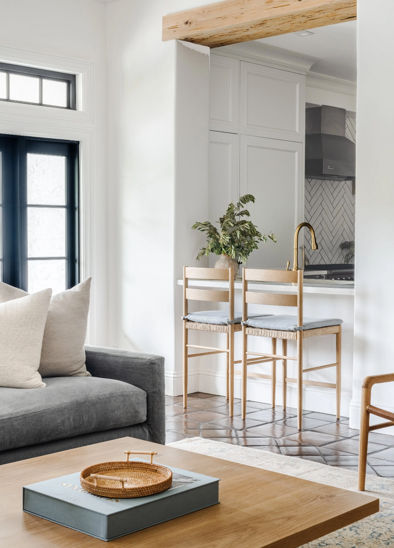 Modern living room with gray sofa, wooden coffee table, and kitchen in the background.