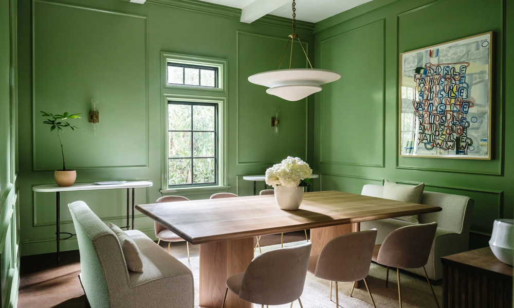 Dining room with green walls, wooden table, and chairs.