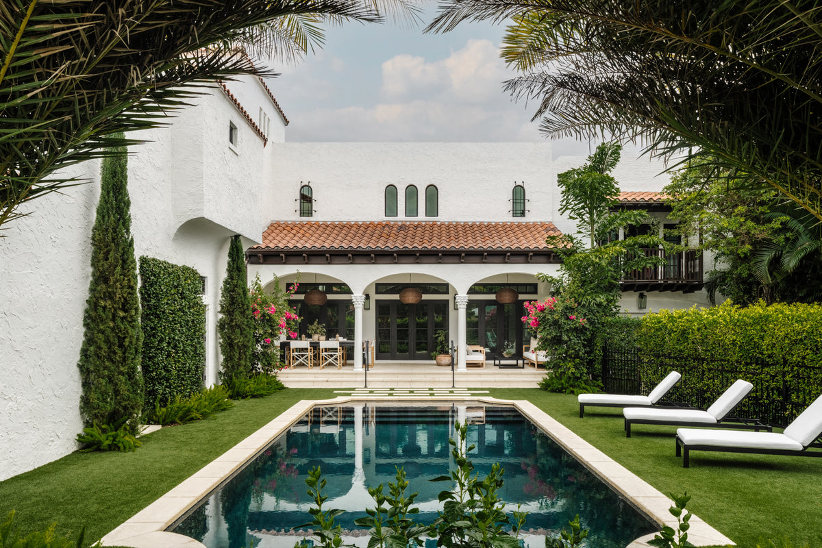 White stucco villa with barrel tile roof, pool, and manicured gardens at Villa Belmonte, West Palm Beach