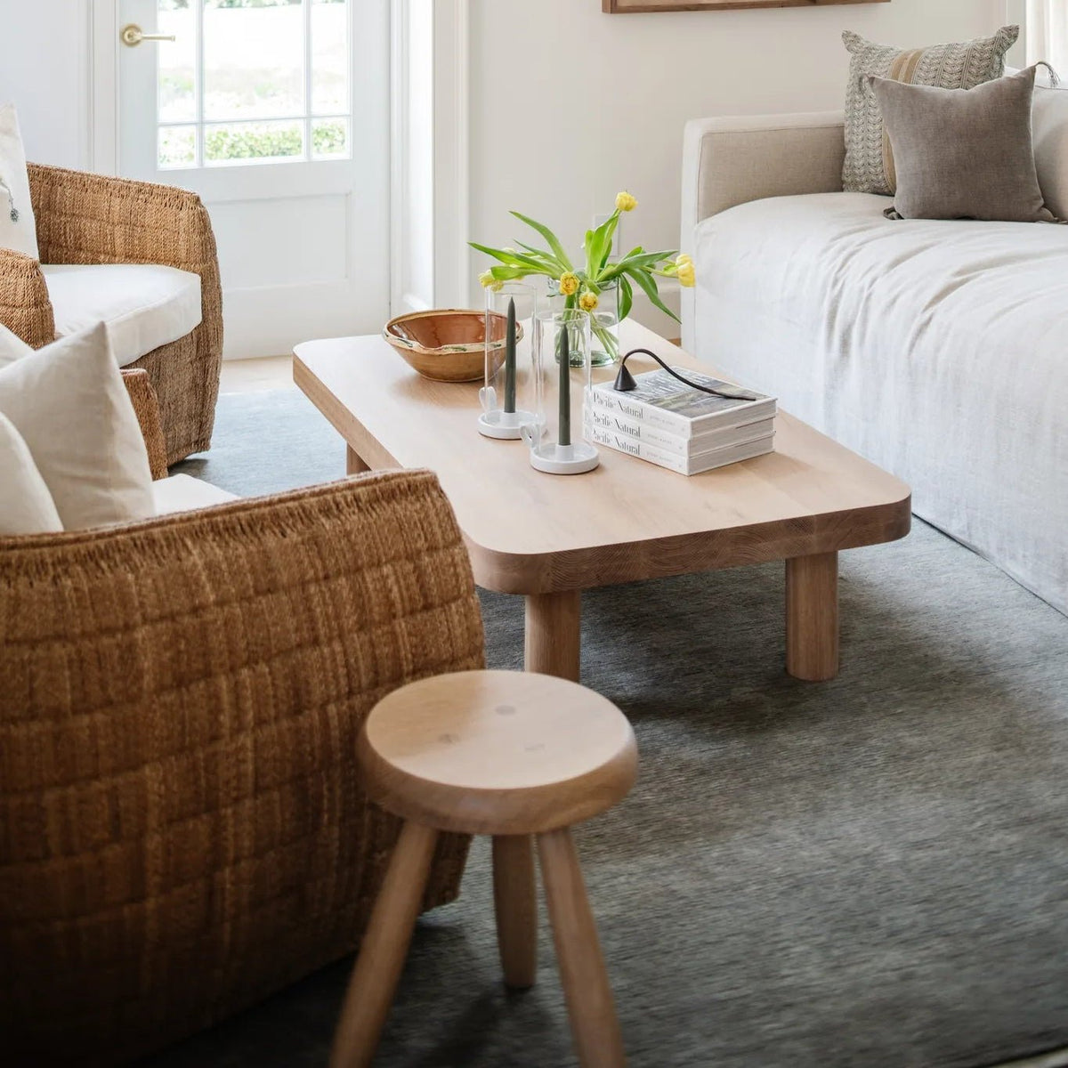 Palma Rectangular Coffee Table in natural oak with woven lounge chairs and an oak stool at Calimia Home