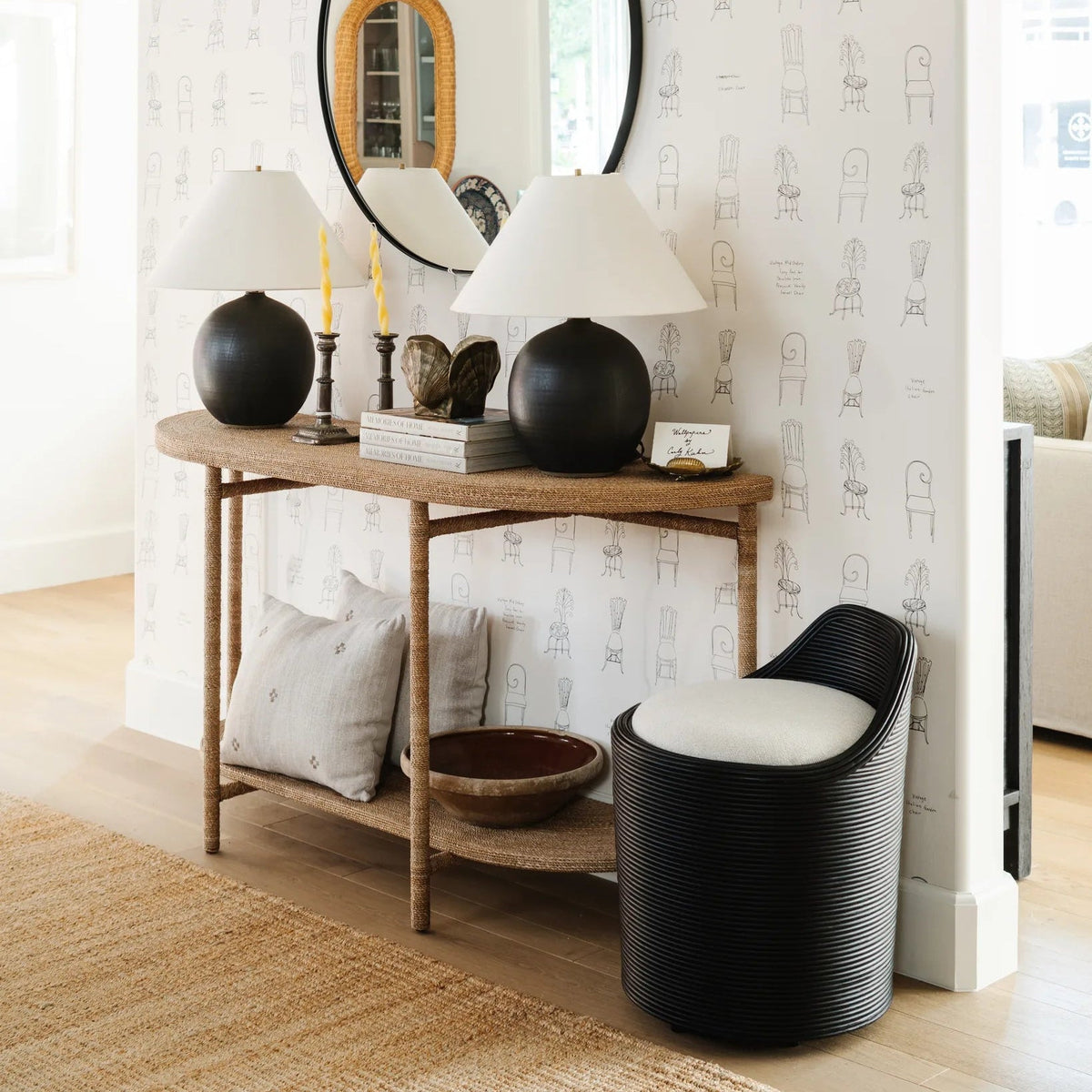 Round Chambers Mirror above a woven console with black ceramic lamps and the Enzo Swivel Accent Chair