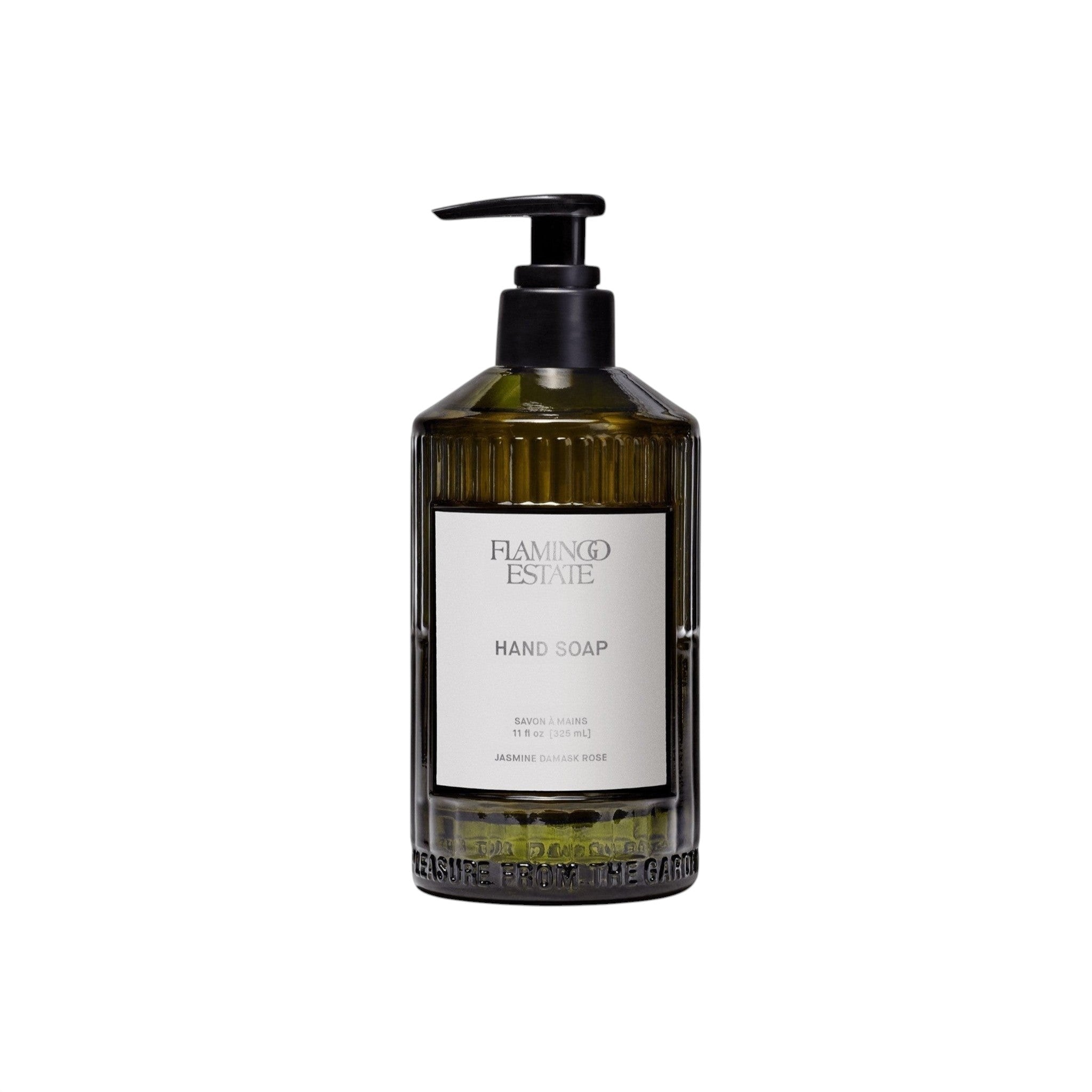 A fluted forest-green glass bottle of Flamingo Estate Jasmine Damask Rose Hand Soap with a white label, on a white background.
