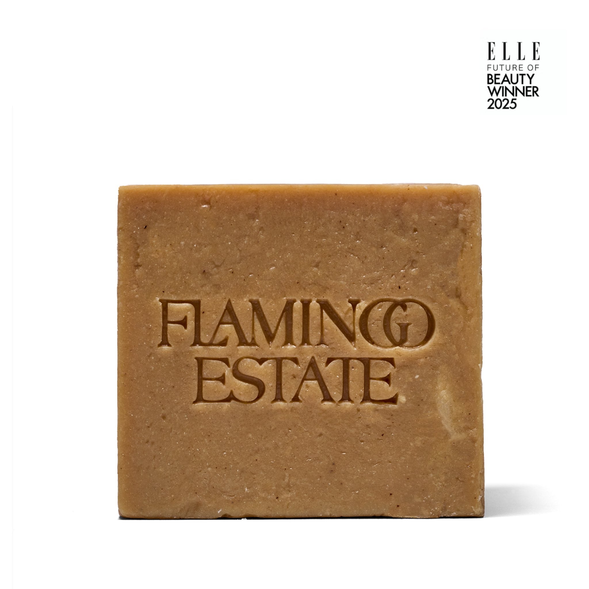 The Manuka Honey Soap Brick from Flamingo Estate, a golden-tan pressed bar embossed with the brand wordmark, photographed on a white background.