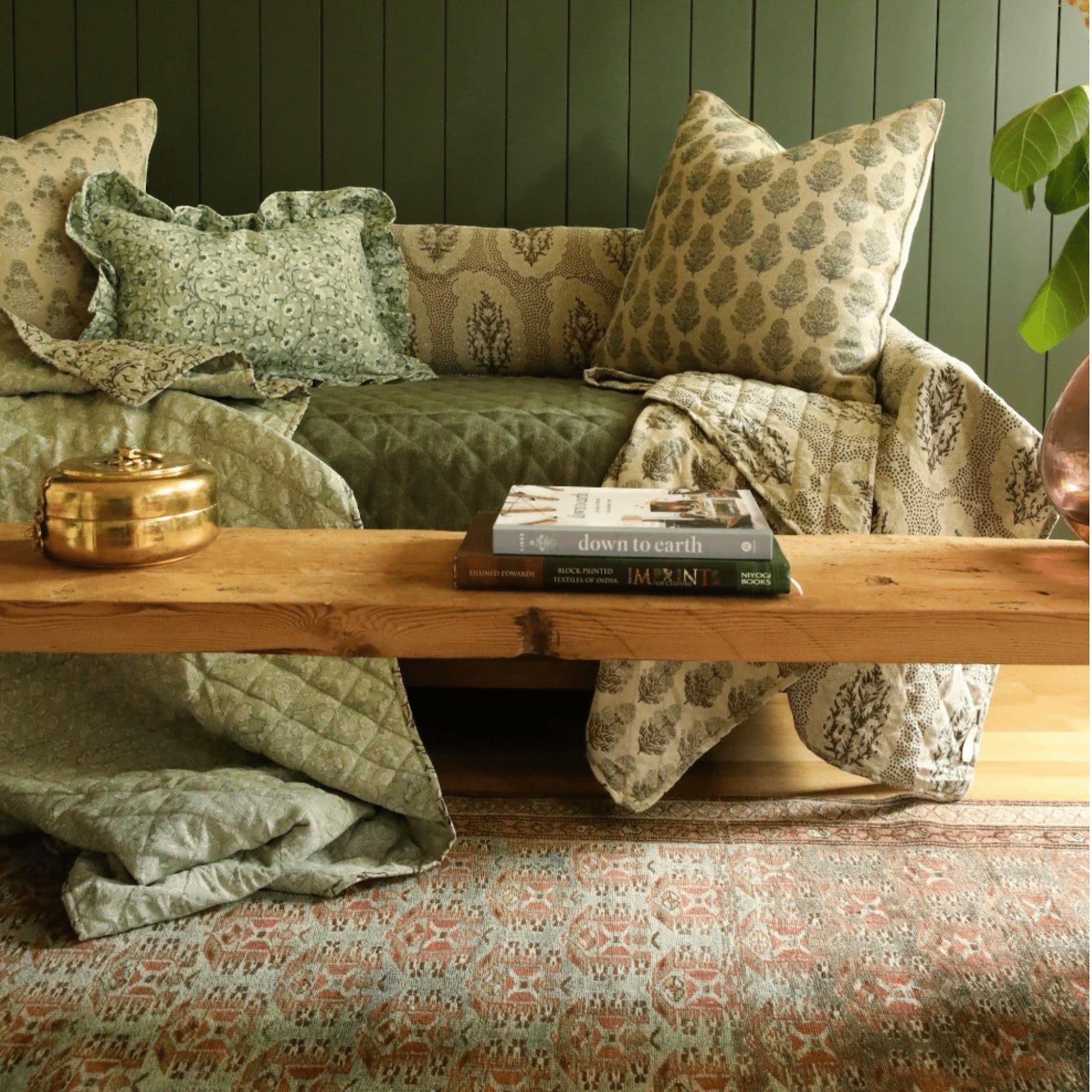 Calimia Home Marigold Graphite linen pillow with hand-block-printed floral motif on a sofa with matching bedding.