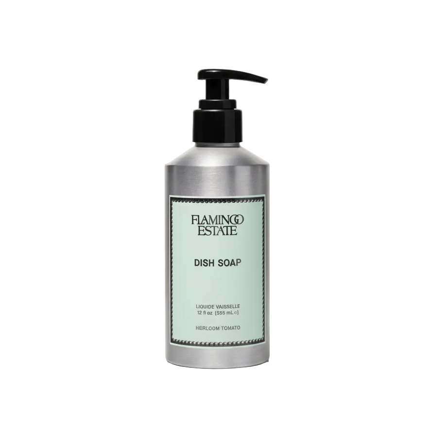 A brushed aluminum Flamingo Estate Heirloom Tomato Dish Soap pump bottle with sage-green label sits centered on a soft cream background.