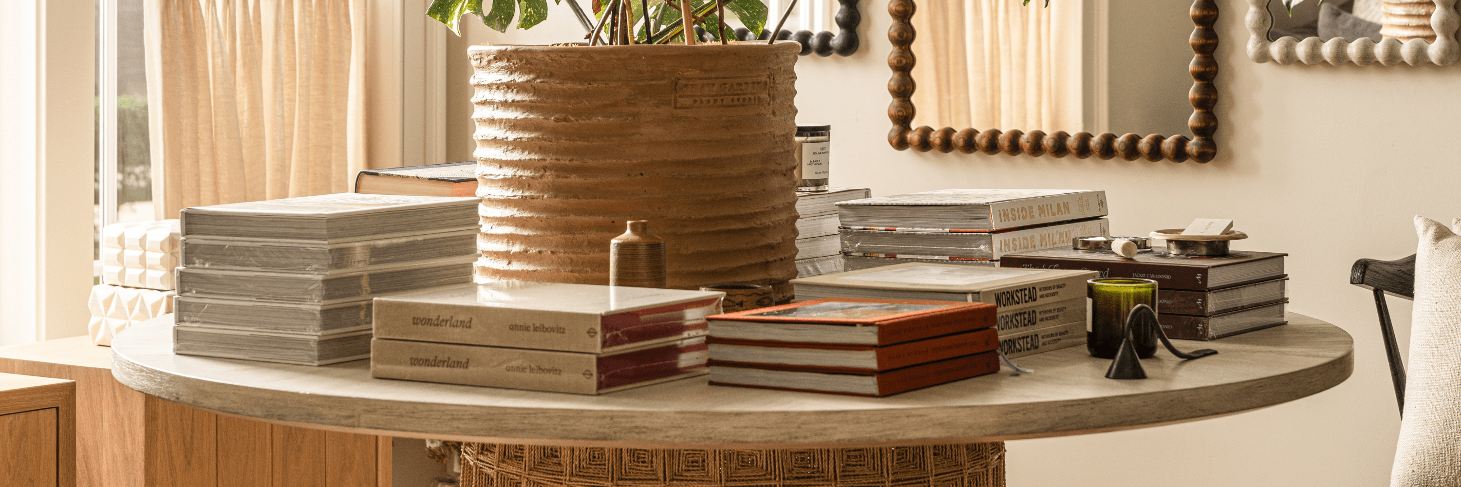 Styled wooden table with fall branches, glassware, books, candles, and baskets in neutral home shop