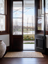 Armadillo River Nook Rug in Natural, handwoven jute rug shown in a room setting