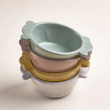 Il Buco Assisi ceramic bowls in a stacked arrangement featuring dove grey, yellow, and sage green hand-glazed finishes.
